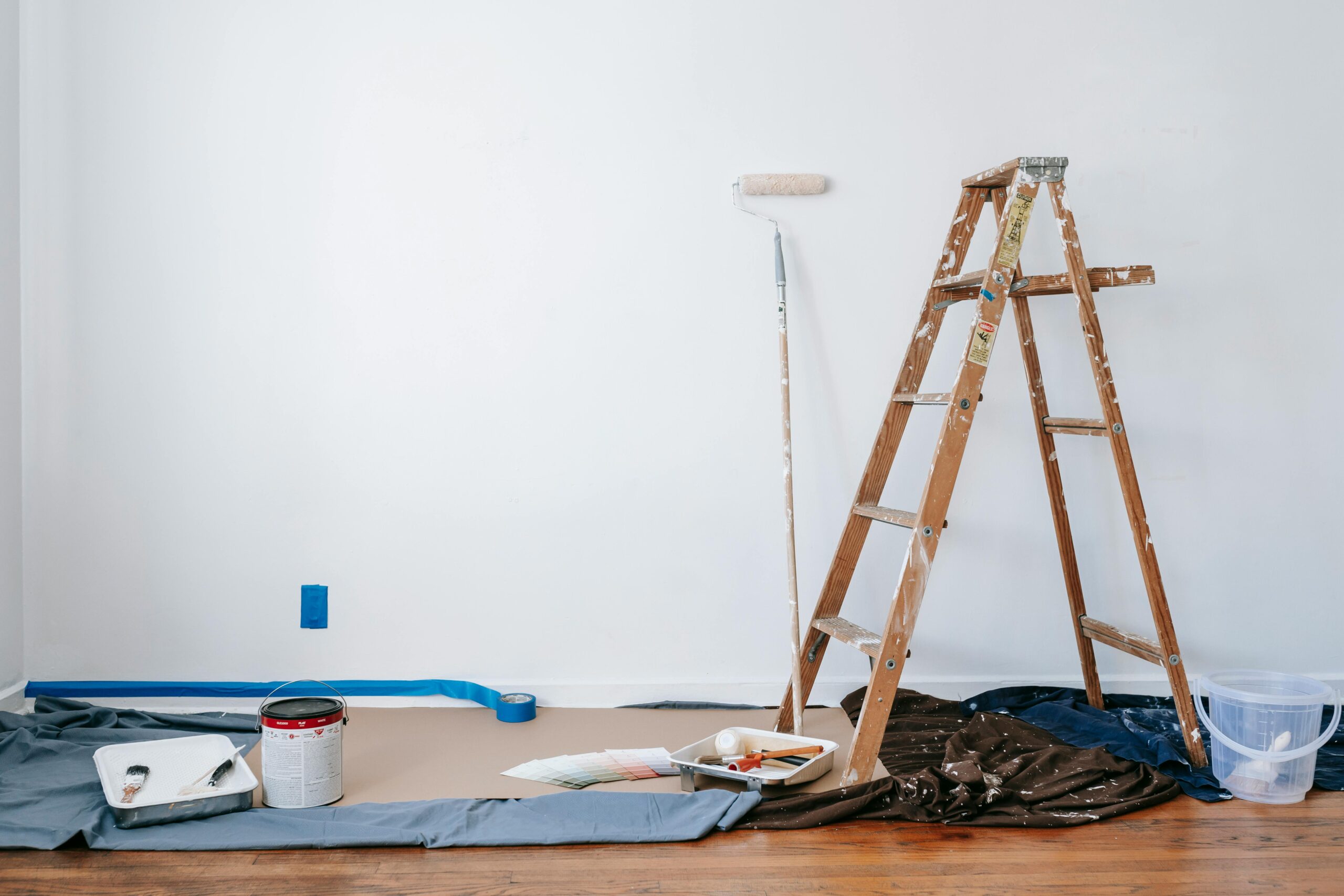 A ladder and paint in a room that appears to be home improvement prep.